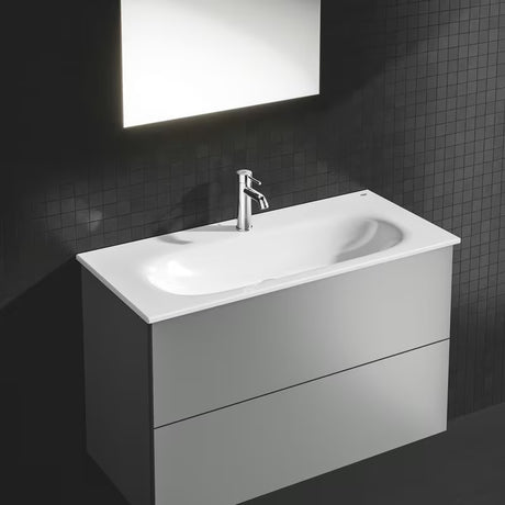 Kromirana enoročna armatura za umivalnik Grohe Essence New z odtočnim kompletom in ukrivljenim izlivom.