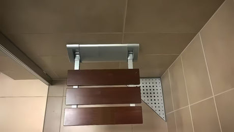Zložljivo sedež za tuš Multi v rjavi izvedbi iz masivnega lesa Bulletwood s stenskim nosilcem.
