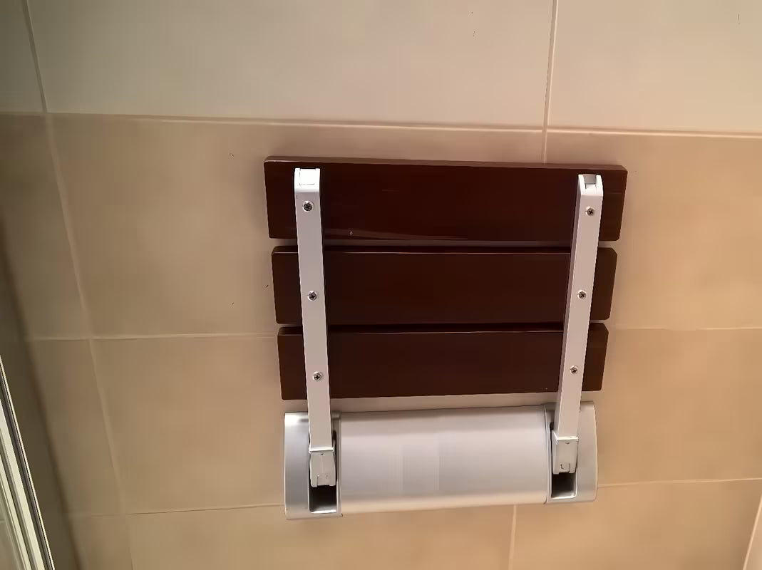 Zložljivo sedež za tuš Multi v rjavi izvedbi iz masivnega lesa Bulletwood s stenskim nosilcem.