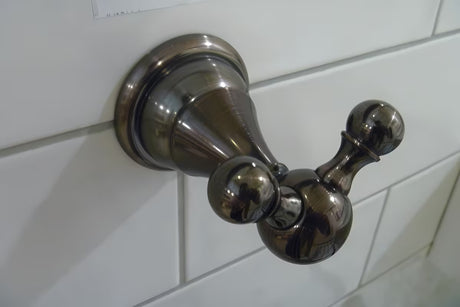 Mesingani stenski dvojni kavelj WF Industrial u završnoj obradi uljno brušena bronca u tamnoj nijansi s bordo odsjajem.